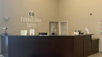 A reception desk with a sign reading "Cobblestone Suites" and a blue mat with the same name.