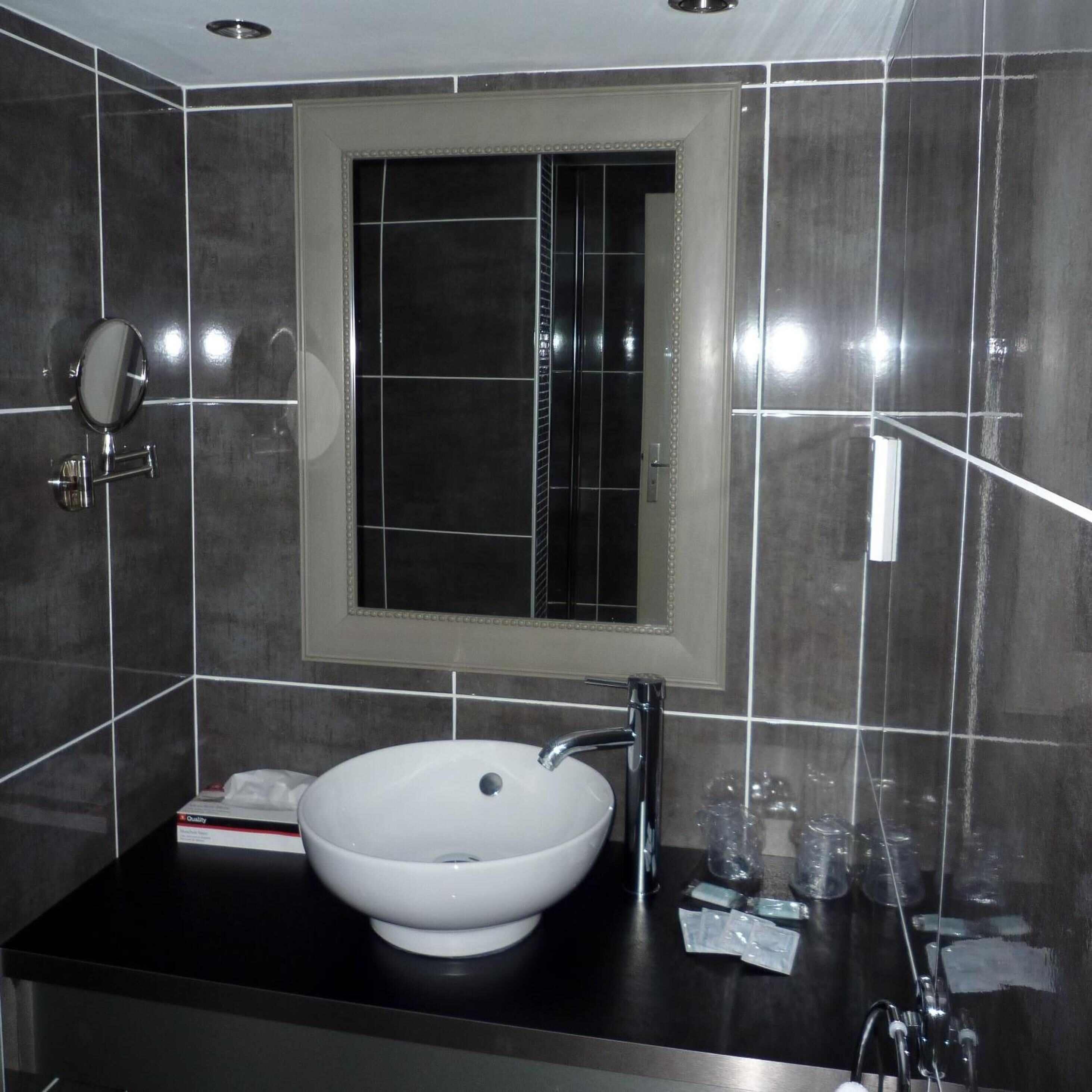 Een moderne badkamer met een wit wastafelmeubel, een spiegel en een raam.