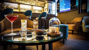 Zona de bar con una mesa redonda, una copa de martini, un vaso de cerveza, un bol de frutos secos y una campana para postres.
