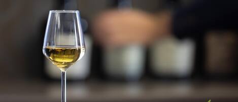A glass of white wine on a table with various cheeses and crackers.