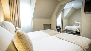 A hotel room with two beds, a TV, and a window with curtains.