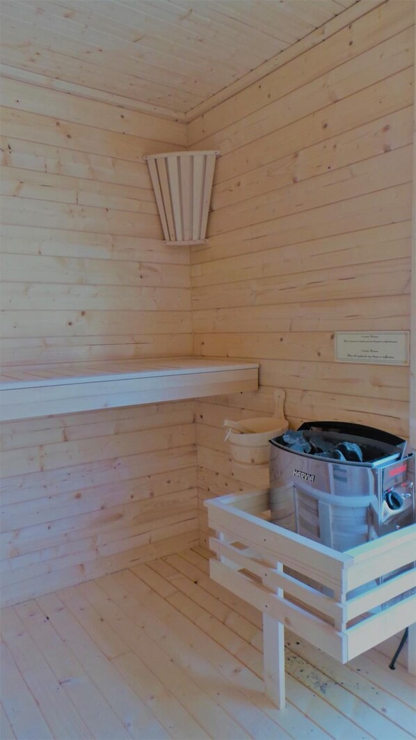 Interior de una cabaña de madera con sauna, estante y calentador de sauna.