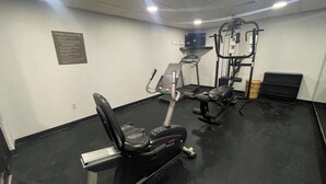 Ein Fitnessstudio mit Cardiogeräten, Krafttrainingsgeräten und einem an der Wand befestigten Fernseher.