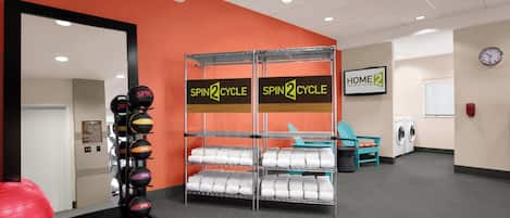 A gym with orange walls, a mirrored wall, and a rack of exercise balls.