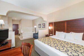 Een hotelkamer met een bed, een bureau met een televisie, een stoel, een badkamer en een douche.