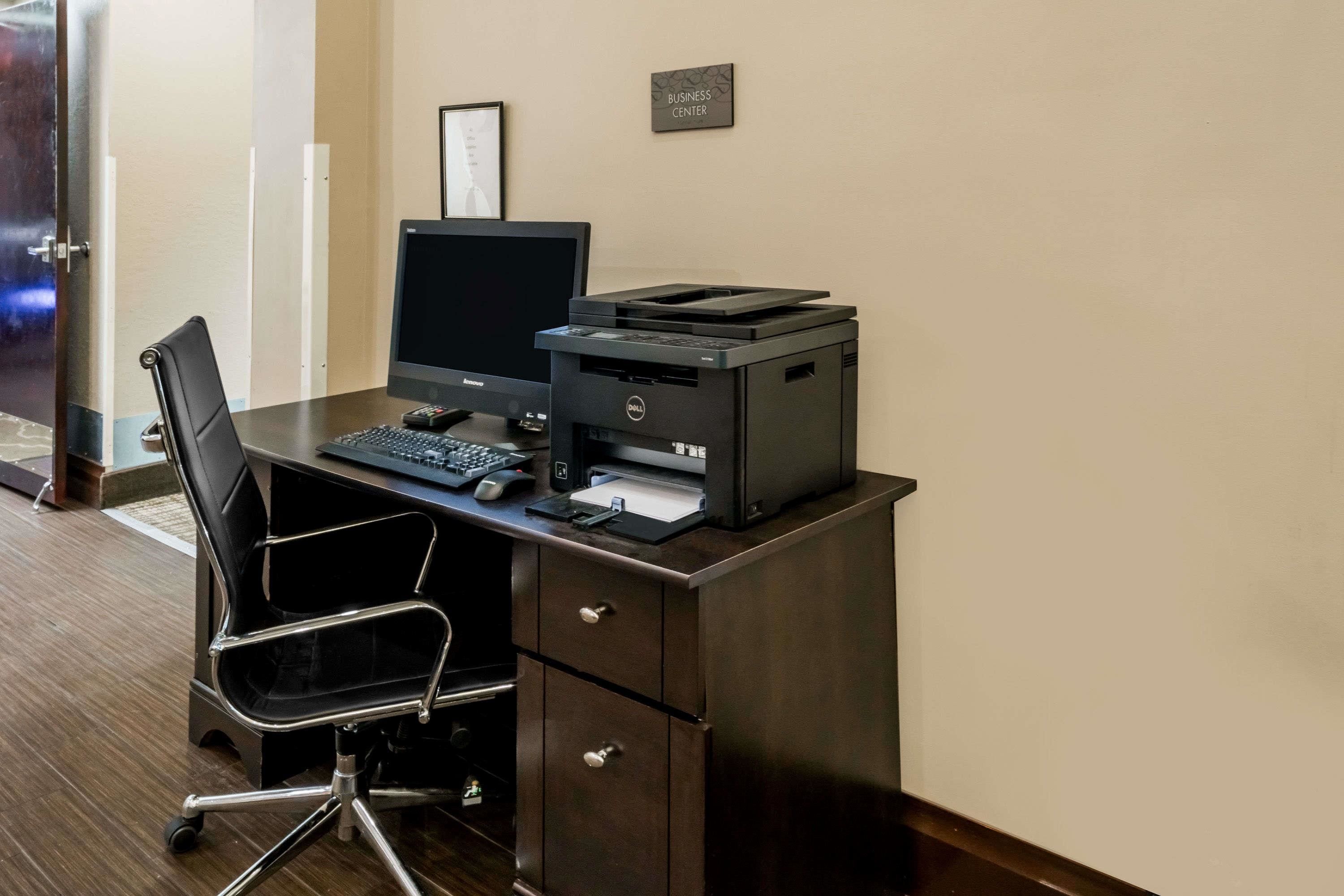 A business center desk with a computer, printer, and chair.