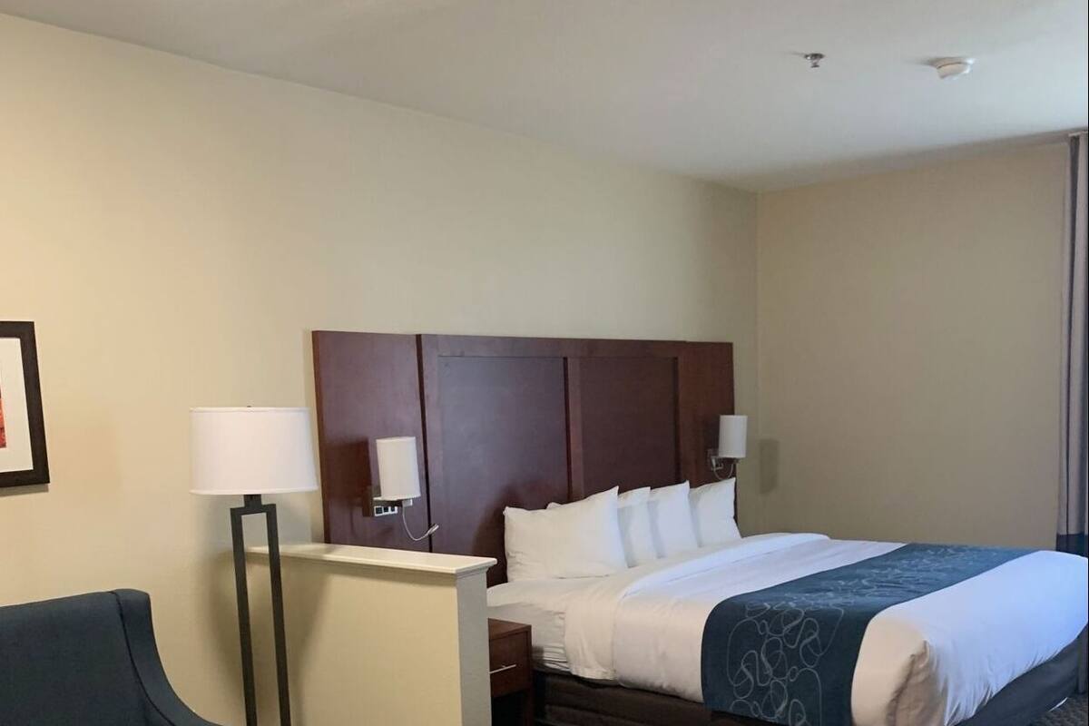 Une chambre d’hôtel avec un lit, un bureau, une chaise et un petit pouf.