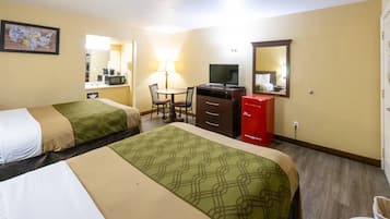 Habitación de hotel con dos camas, un escritorio con silla, televisor, un armario rojo y un espejo en la pared.