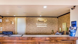 Una reception con finitura in legno, un cartello con la scritta 'EconoLodge' e una brochure con la scritta 'Benvenuti'.