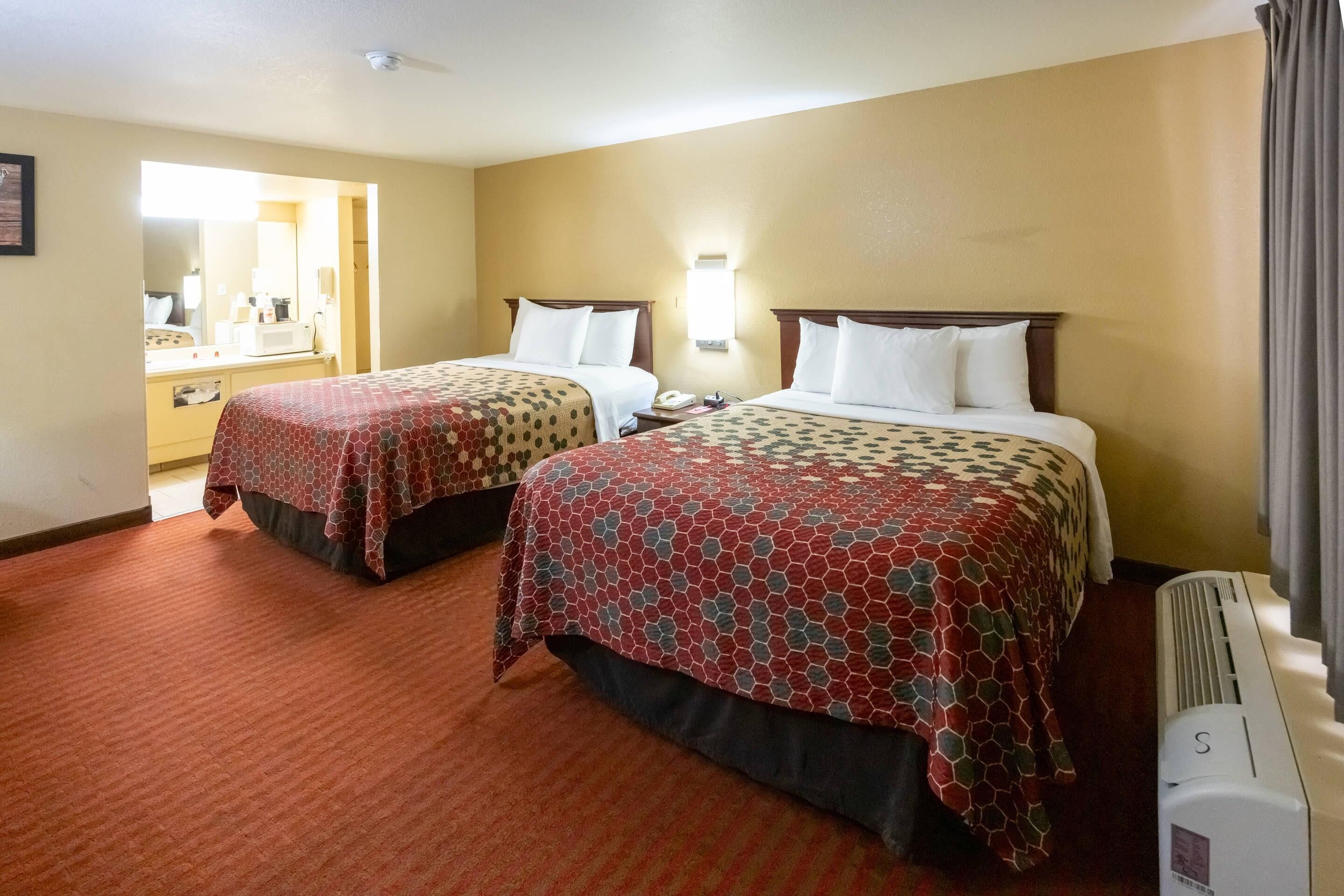Ein Hotelzimmer mit zwei Betten, einem Schreibtisch und einem Spiegel.