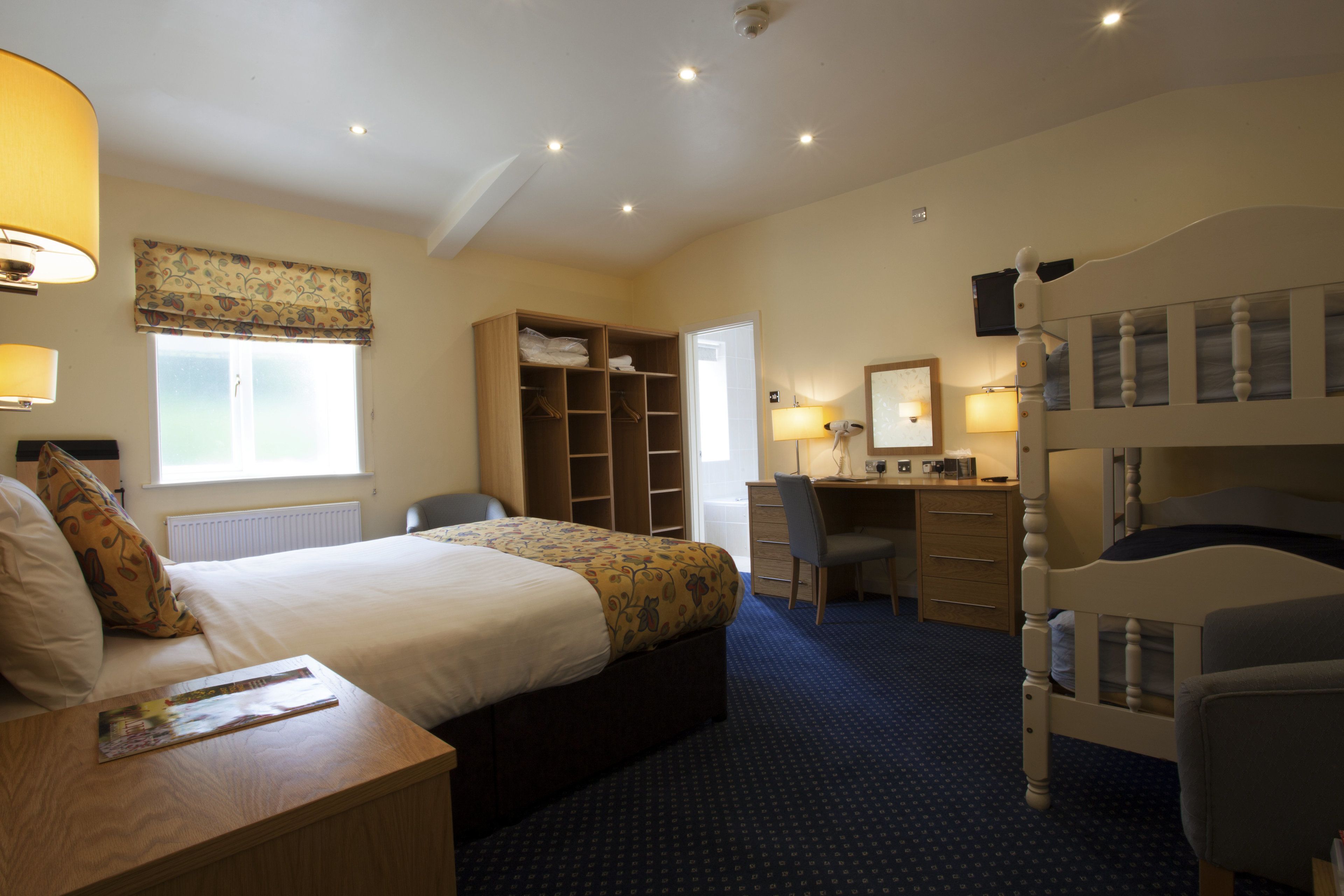 أسرّة بطبقة علوية مريحة وخزنة داخل الغرفة ومكتب