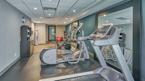 Un gimnasio con cintas de correr, elíptica y bicicleta estática.