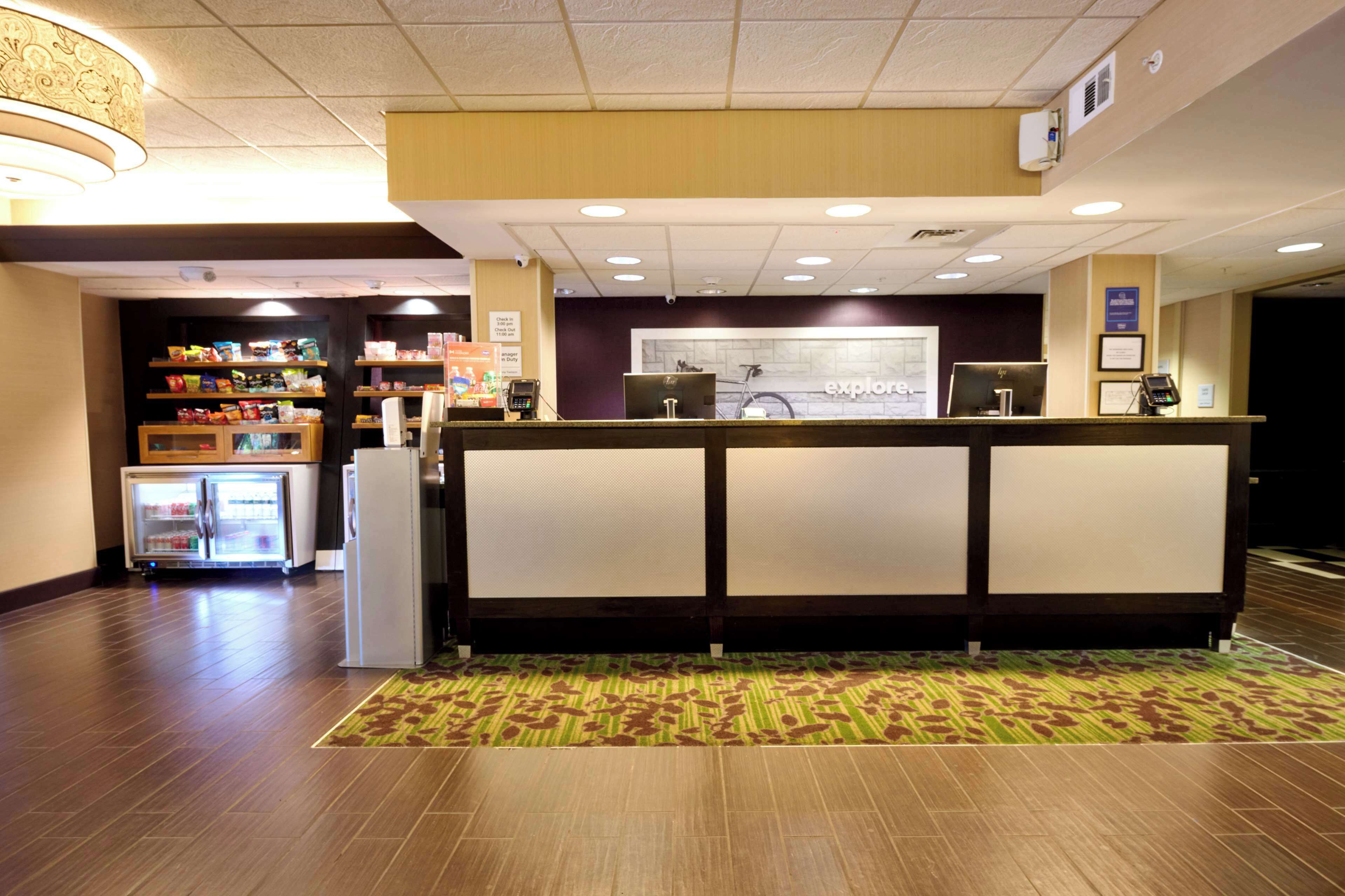 A reception area with a counter, a refrigerator, and shelves with snacks.