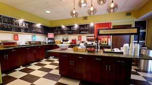 Una cocina con suelo de cuadros, armarios de madera y una isla central con diversos utensilios.