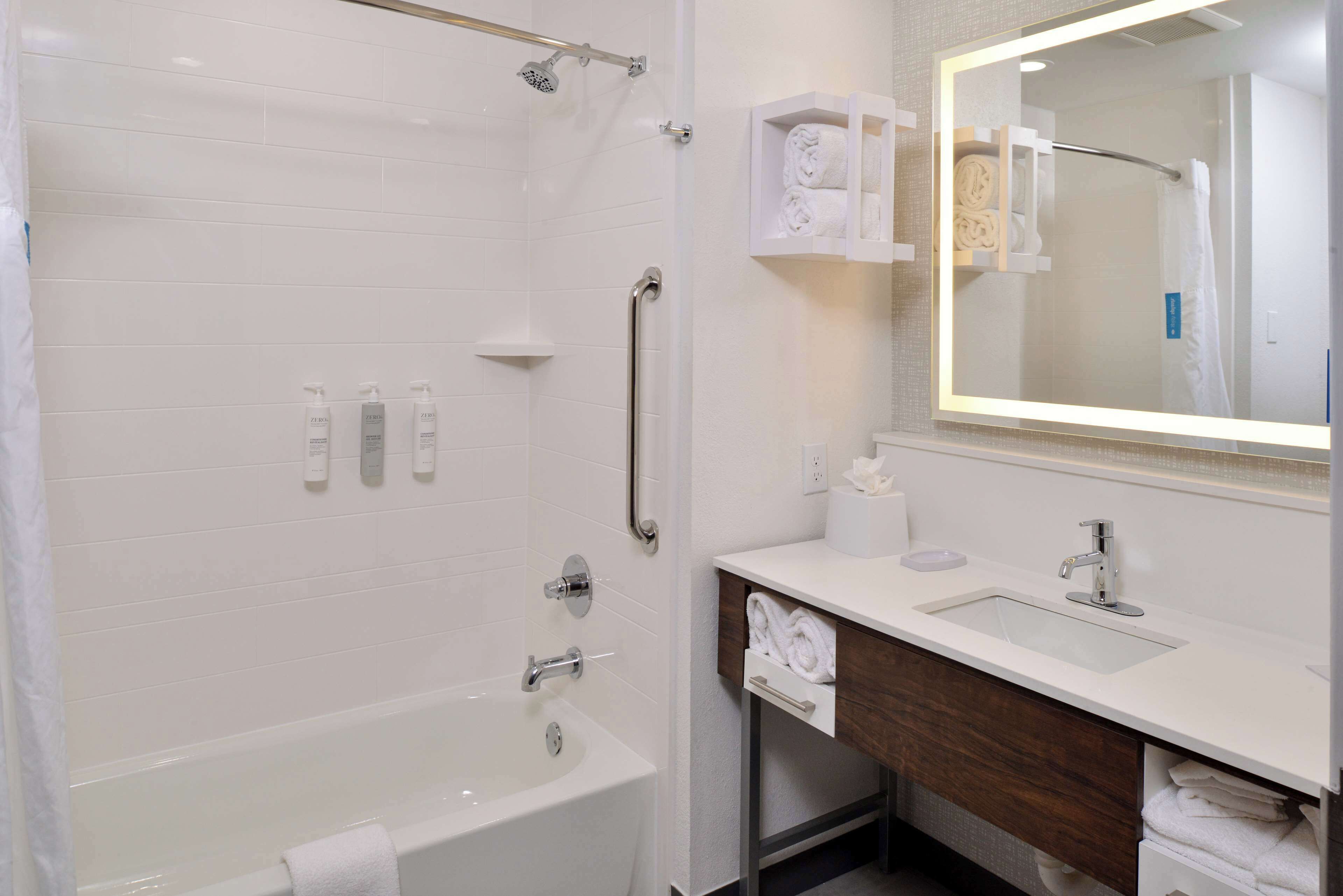 Un baño moderno con cabina de ducha, bañera, lavamanos y tocador con espejo.
