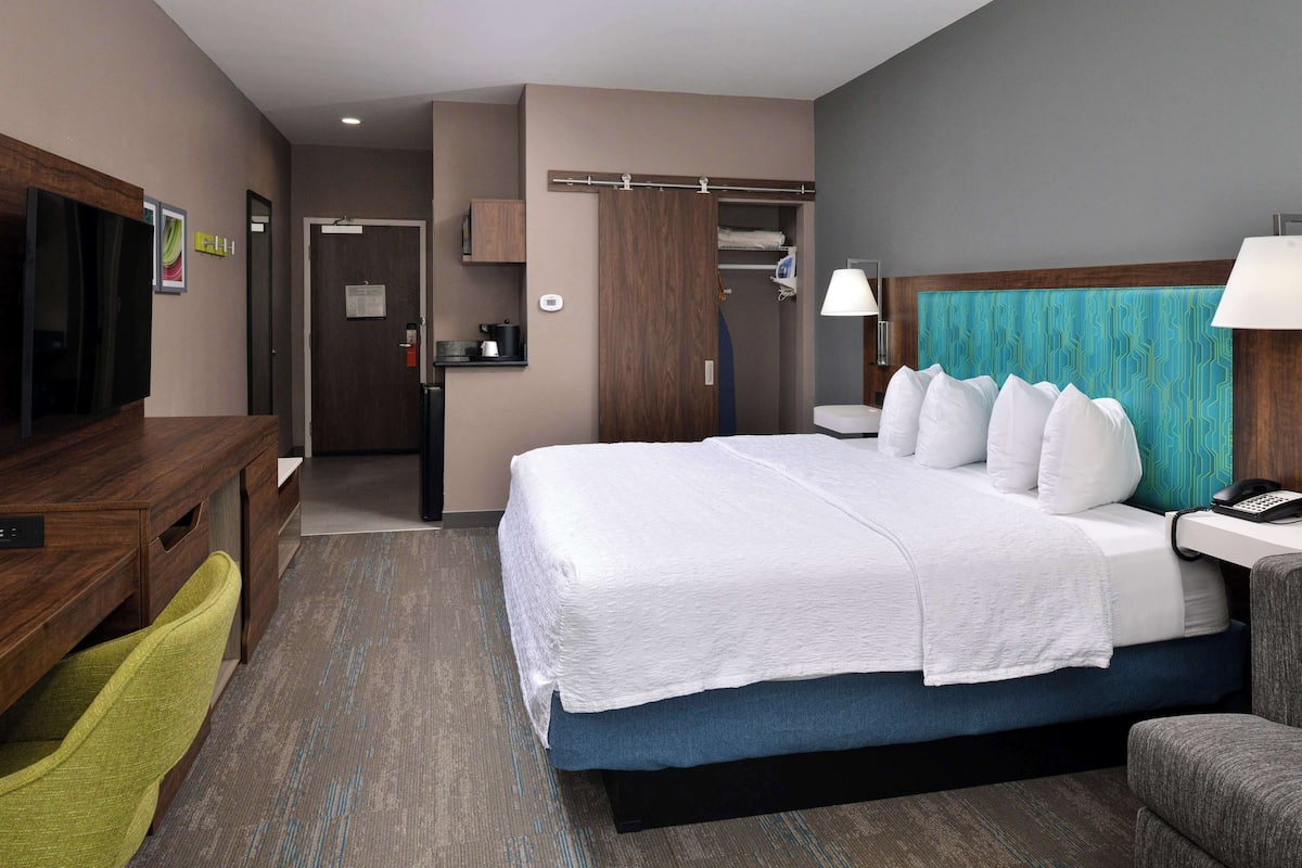 Hotelkamer met een groot bed, een bureau, een stoel, een televisie en een badkamer met douche en toilet.