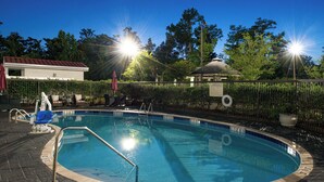 Una piscina con borde de azulejos, una escalera metálica y una valla alrededor.