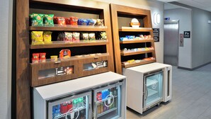 Un área de venta automática con opciones de bocadillos y bebidas, como papas fritas, galletas y bebidas embotelladas.