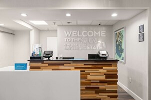 Un mostrador de recepción con diseño de madera, un cartel que dice 'Bienvenidos al Estado Sol, Brillo' y un cartel de 'Hilton Honors'.