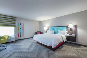 Una habitación de hotel moderna con una cama grande, un escritorio y una silla.
