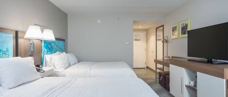 A hotel room with two beds, a TV, a desk, and a wardrobe.