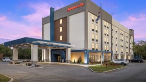Un hôtel Hampton Inn doté d’une façade moderne, d’une entrée abritée et d’une enseigne accueillante.