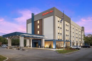 Un hotel Hampton Inn con fachada moderna, entrada cubierta y un cartel acogedor.