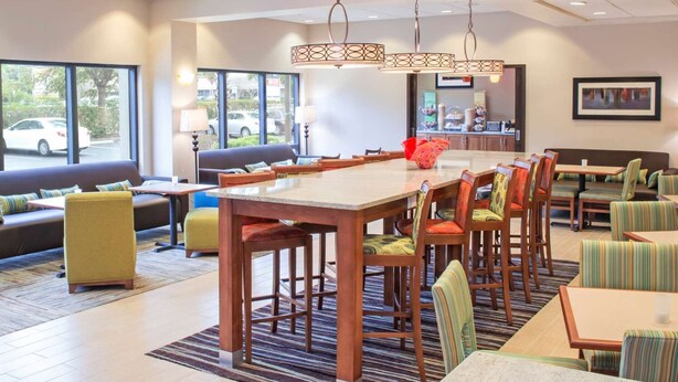 Un hall d’hôtel spacieux, doté d’une grande table à manger, de sièges confortables et de grandes fenêtres donnant sur la rue.