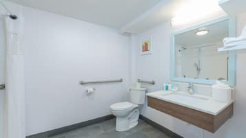 A modern bathroom with a white toilet, a sink with a mirror, and a shower area.