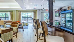 A restaurant with a bar area, seating arrangements, and a refrigerator stocked with beverages. - Hampton Inn Wilmington-Medical Park (Wilmington)