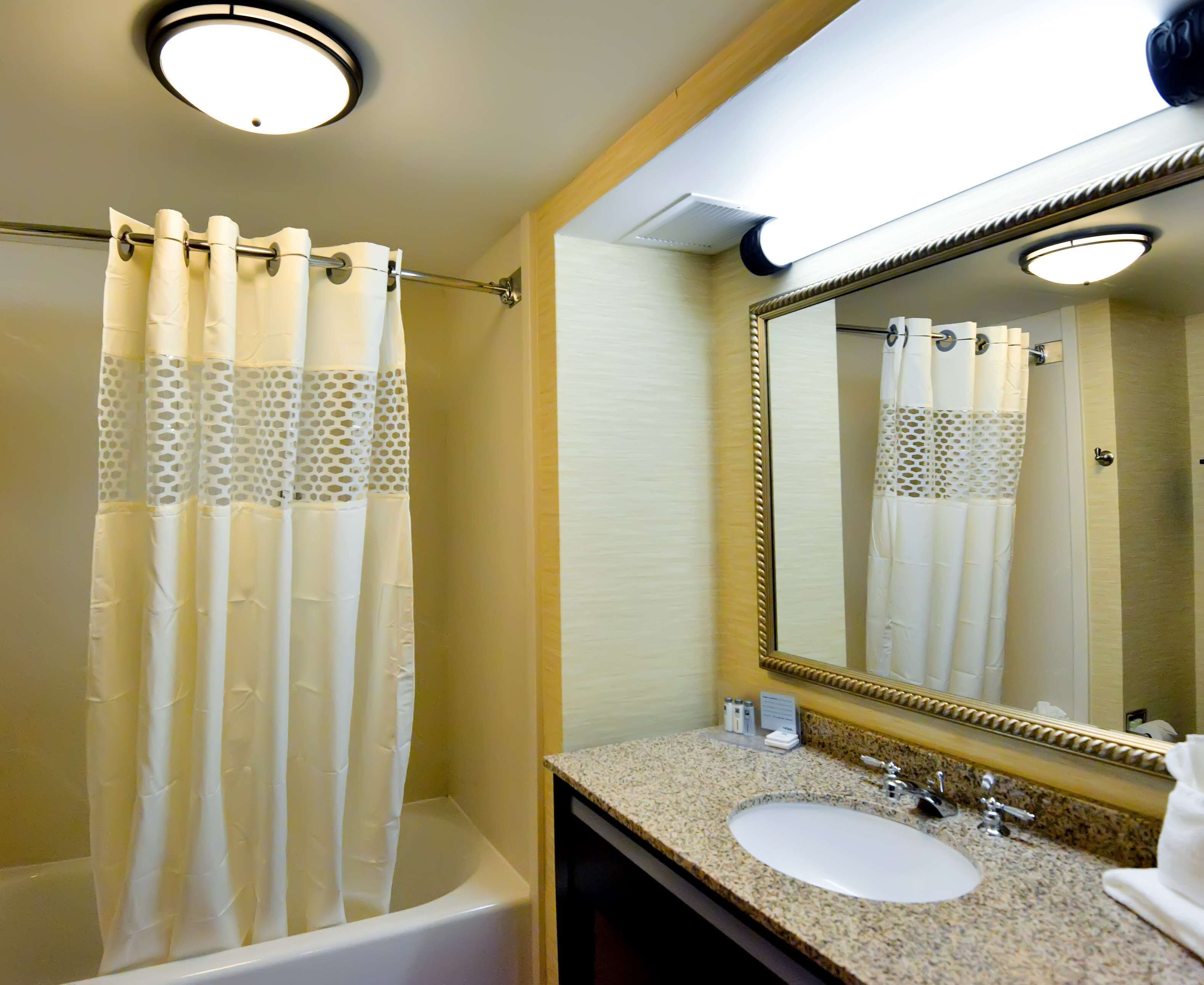 A bathroom with a bathtub, a sink, a mirror, and a shower curtain.