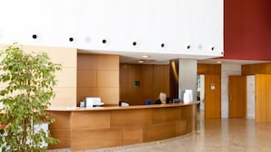A reception area with a wooden reception desk, a potted plant, and a red accent wall.