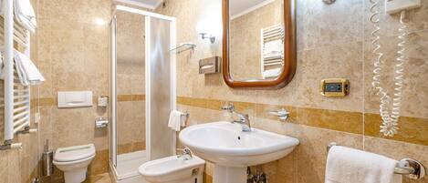 Baño con inodoro, bidé, lavamanos y zona de ducha.