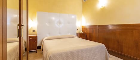 A hotel room with a large bed, bedside tables, and a wooden headboard.