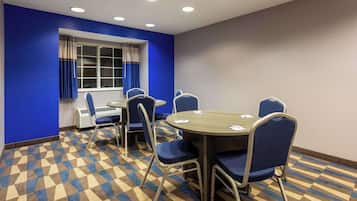 Un salón de conferencias con piso a cuadros, paredes azules y un amplio ventanal con cortinas.