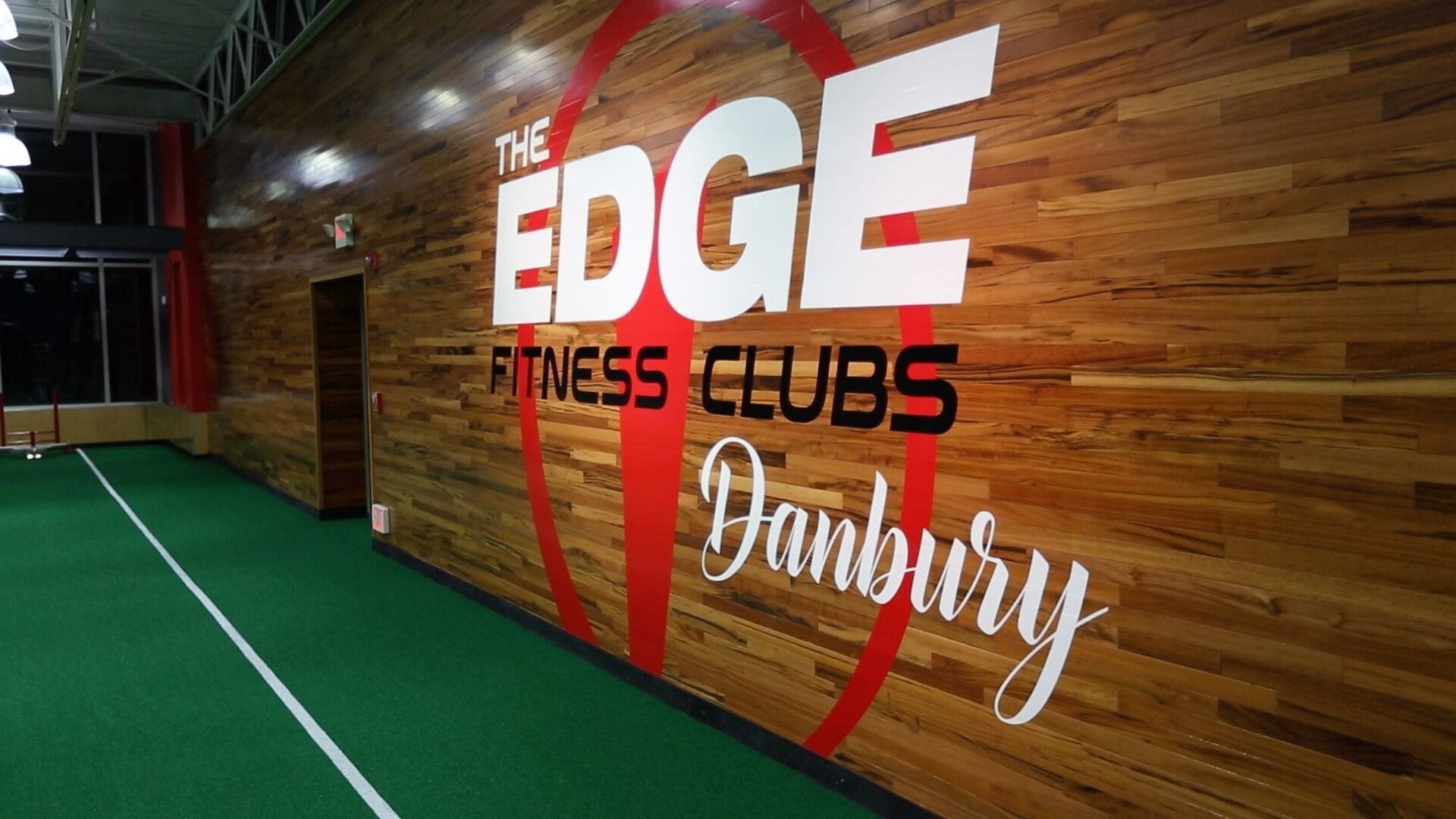 A wall with "THE EDGE FITNESS CLUBS" signage and a green carpeted floor.