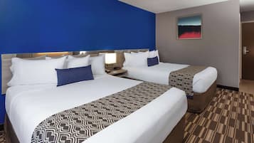 A hotel room with two beds, a patterned bedspread, and a painting on the wall.