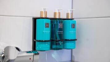 Une salle de bain avec trois flacons de shampoing, d’après-shampoing et de gel douche de la gamme Ritual of Kare.