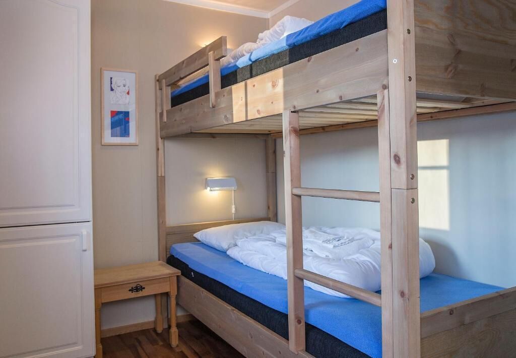 A bunk bed room with a bedside table and a lamp.