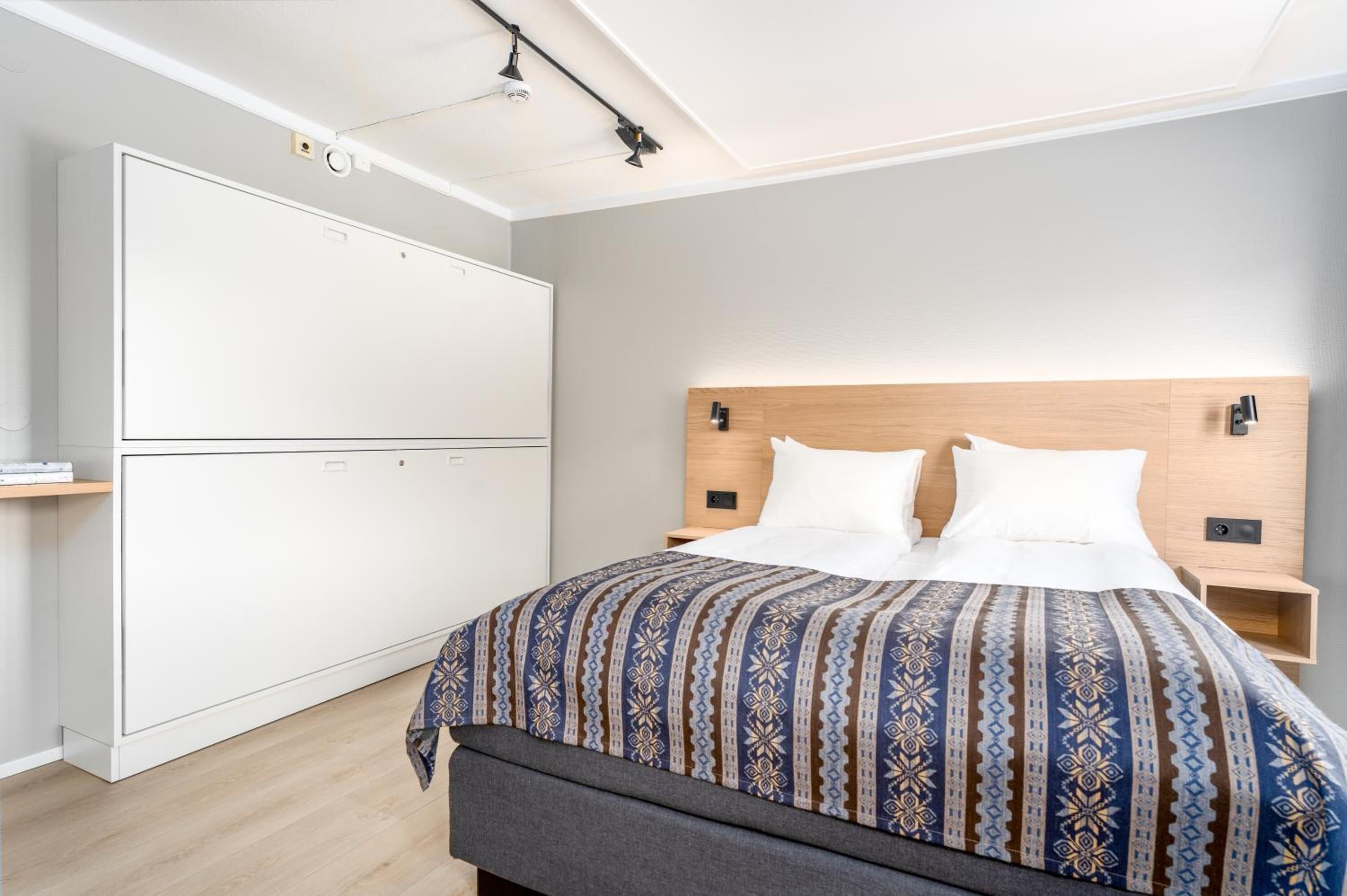 A bedroom with a bed, bedside tables, a wardrobe, and a bench.