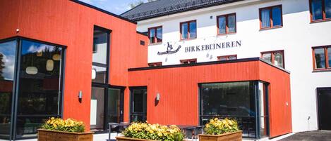 A building with a red and white facade, large windows, and a sign reading "BIRKEBEINEREN".