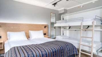 Una habitación de hotel moderna con una cama grande, una cama litera y una escalera.