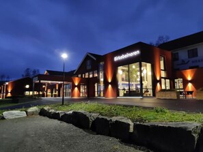 A building with a sign reading "Birkebeineren" at night, featuring large windows and a well-lit entrance.