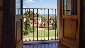 Puerta abierta que da a un balcón con vistas a una zona residencial y un cielo despejado.