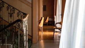 Una escalera de mármol con barandillas de metal decoradas que conduce a una habitación con una silla y una mesa.