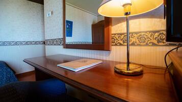 A wooden desk with a lamp, a mirror, and a notebook.