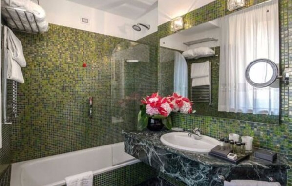 A bathroom with a green mosaic wall, a white sink, and a mirror.