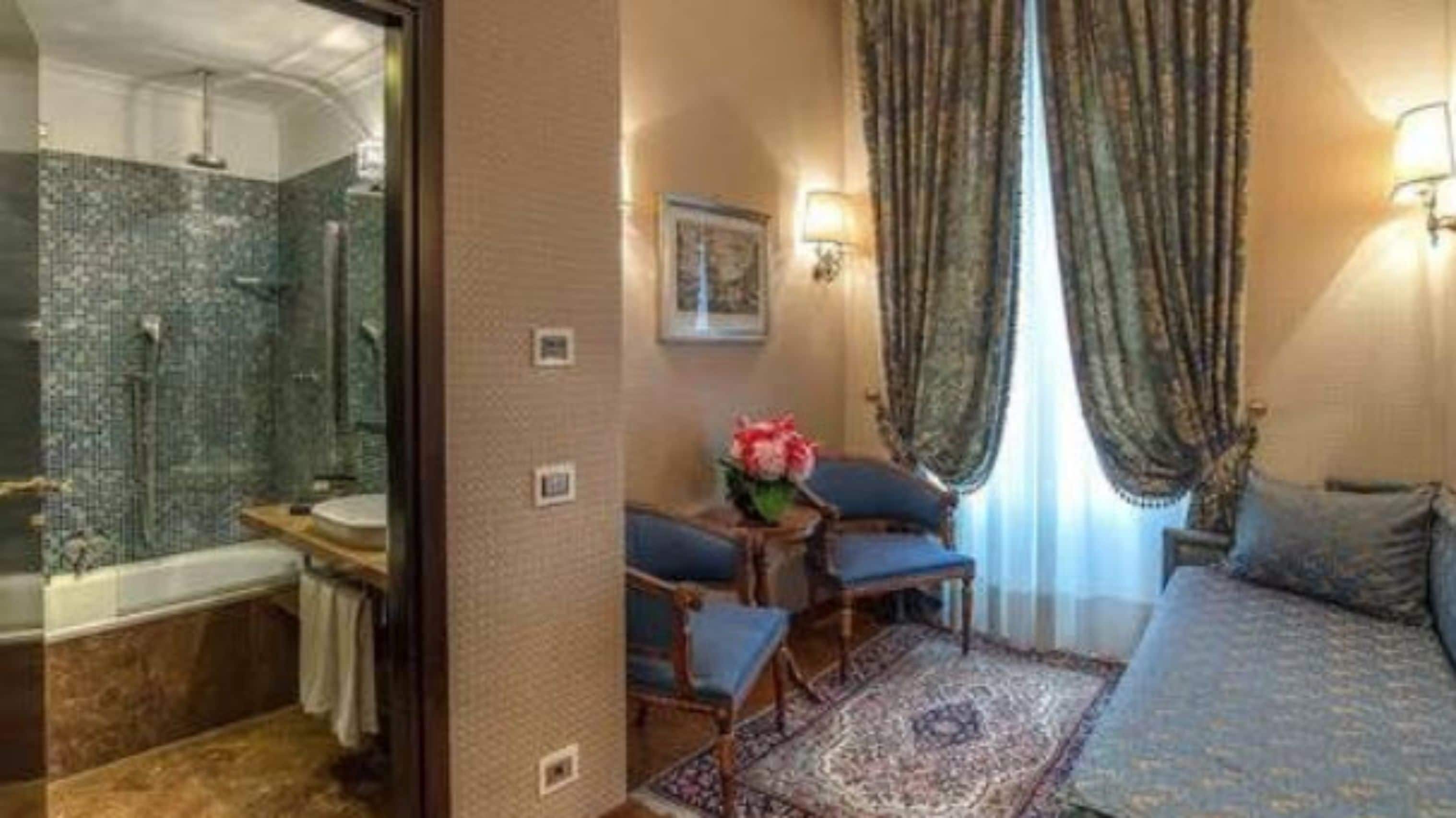 Une chambre d’hôtel comprenant une salle de bain, un lit, une chaise, un tapis et des rideaux.