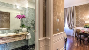 Un baño con lavamanos de mármol, un espejo y una orquídea en maceta.