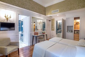 A hotel room with two beds, a TV, a desk with a chair, and a bathroom with a shower and toilet.